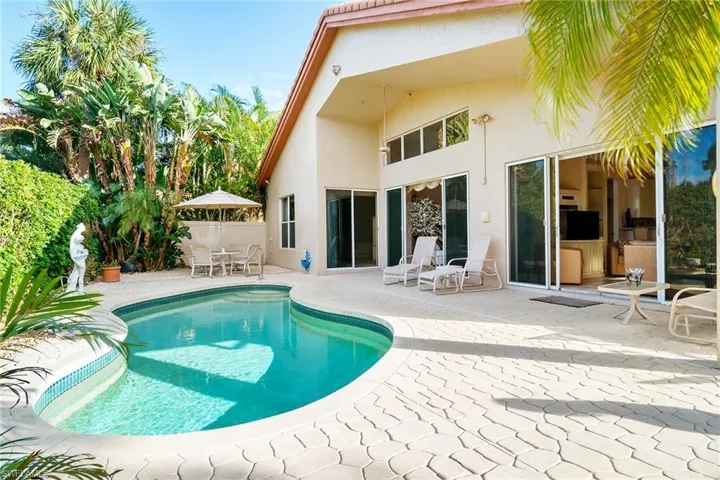 Back of property with a fenced in pool and a patio area