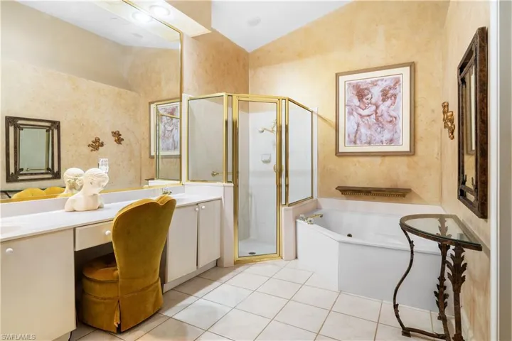 Primary Bathroom featuring tile patterned flooring, vanity, vaulted ceiling, and plus walk in shower