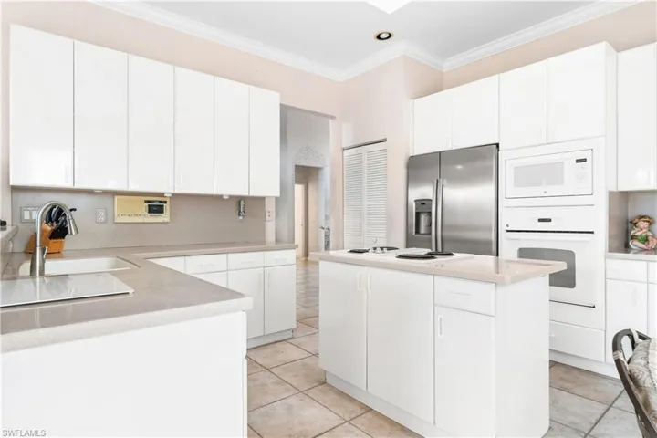 Kitchen featuring a center island, white appliances, sink, and white cabinetry