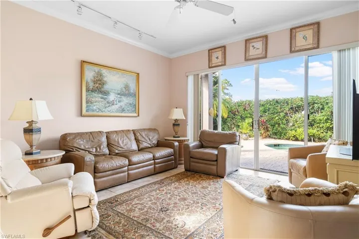 Living room featuring ornamental molding, rail lighting, ceiling fan, and a healthy amount of sunlight