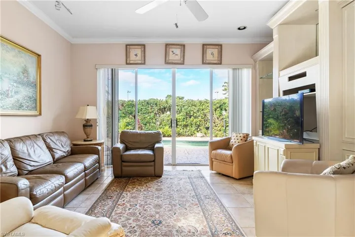Tiled living room featuring ceiling fan and ornamental molding