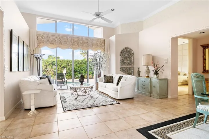 Living room featuring crown molding, a towering ceiling, ceiling fan, and light tile patterned floors