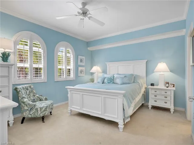 Primary Bedroom with Crown Molding, Ceiling Fan, & Arched Windows with Plantation Shutters