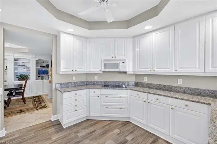 Kitchen featuring a tray ceiling, light stone countertops, recessed lighting, and white cabinets