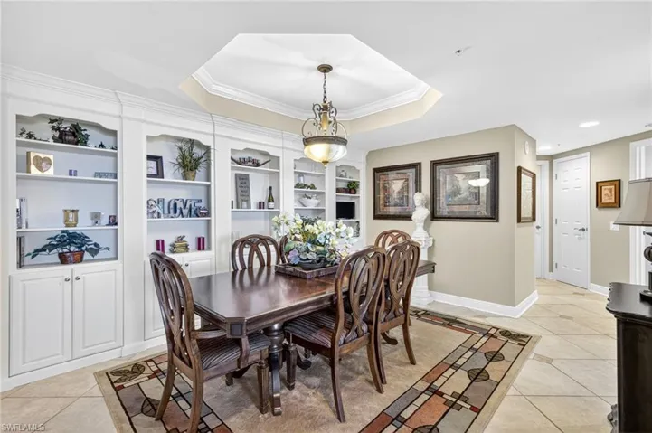 Dining room featuring light tile patterned floors, a tray ceiling, and crown molding