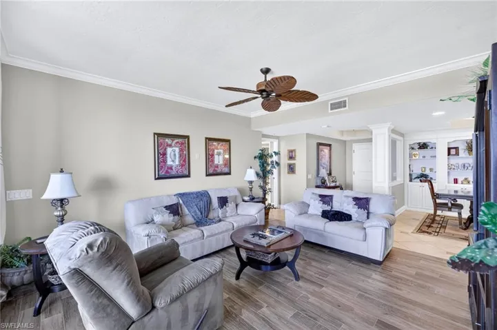 Living room with a ceiling fan, crown molding, and light wood-style flooring