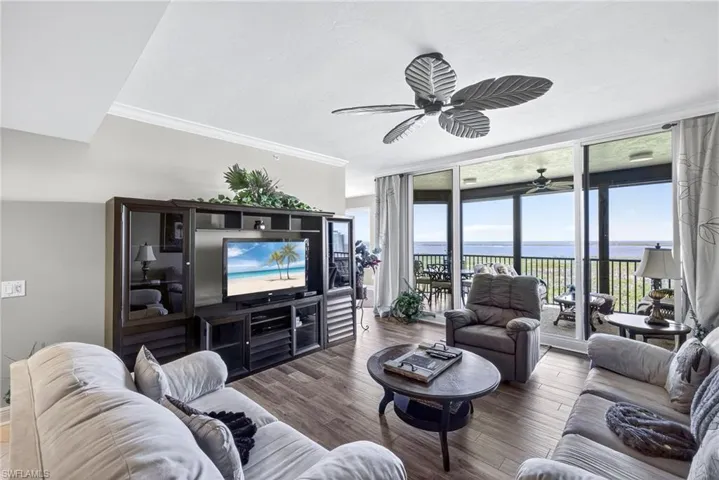 Living area with floor to ceiling windows, crown molding, wood finished floors, and a ceiling fan