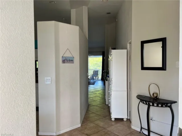 Hallway with tile patterned floors and a textured wall