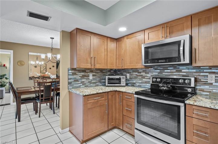 Kitchen has tiled back-splash, granite counter tops, and stainless steel appliances