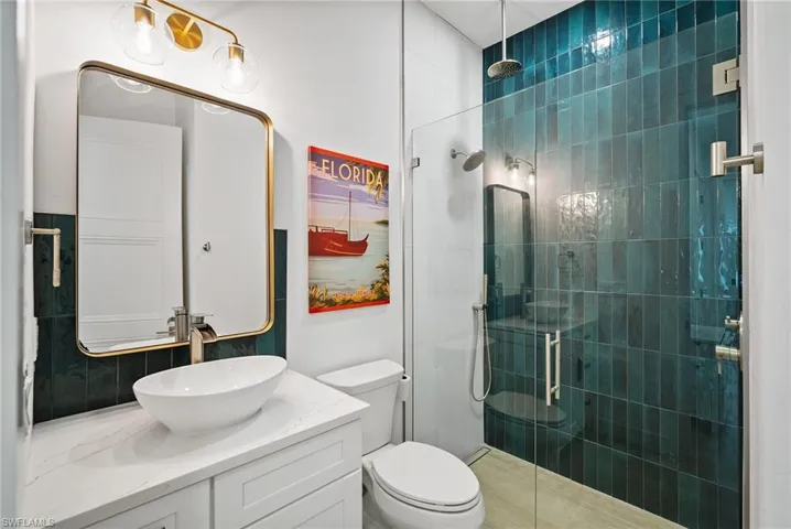 Bathroom featuring vanity, tiled shower, and toilet
