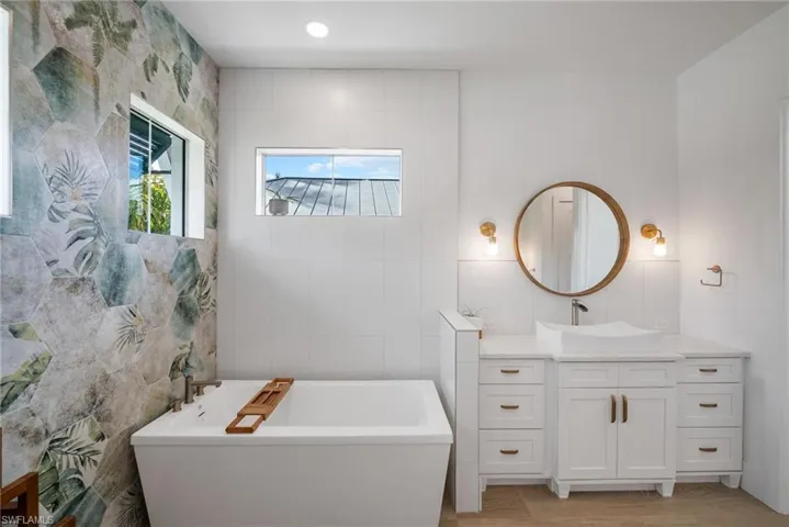 Bathroom with a bathtub, a healthy amount of sunlight, and tile walls