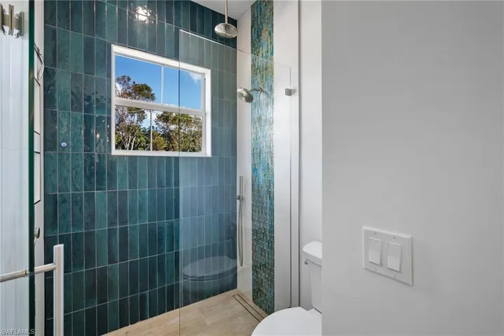 Bathroom featuring tile patterned floors, toilet, and an enclosed shower