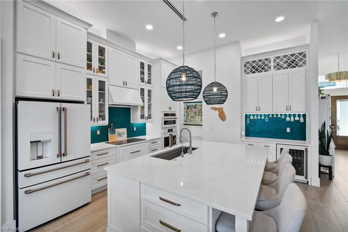 Kitchen featuring a center island with sink, premium range hood, high end fridge, and light hardwood / wood-style floors