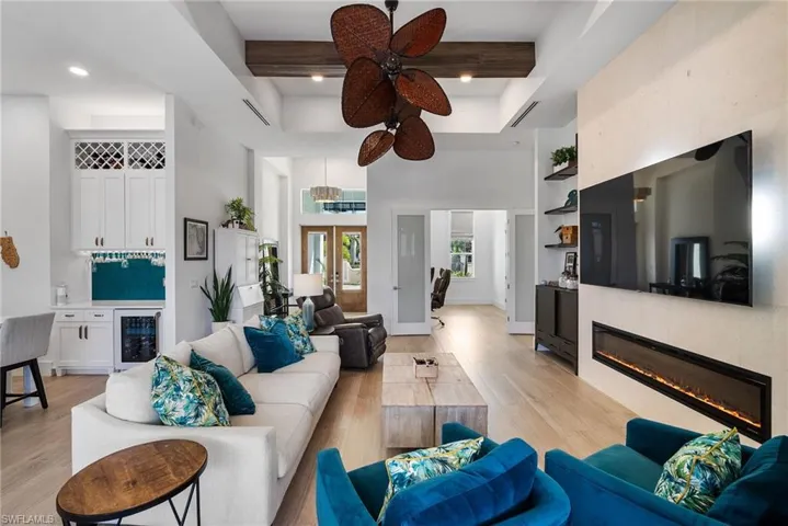 Living room featuring light hardwood / wood-style floors, wine cooler, beamed ceiling, and ceiling fan