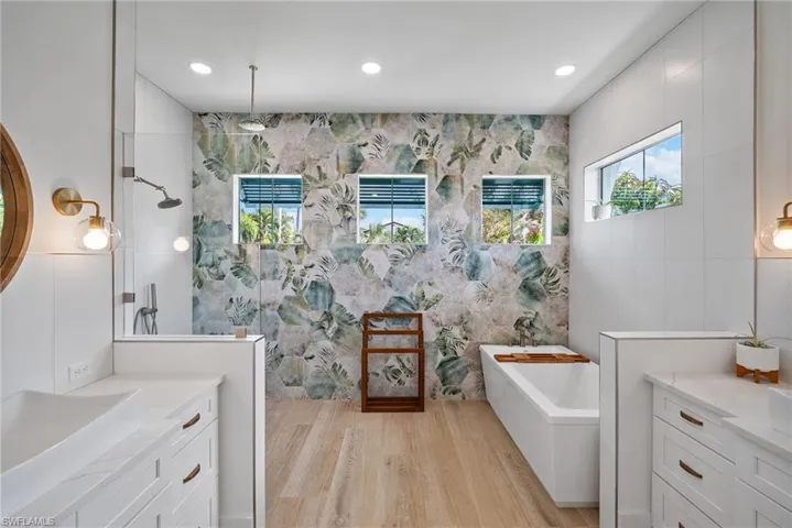 Bathroom featuring vanity, hardwood / wood-style flooring, independent shower and bath, and tile walls