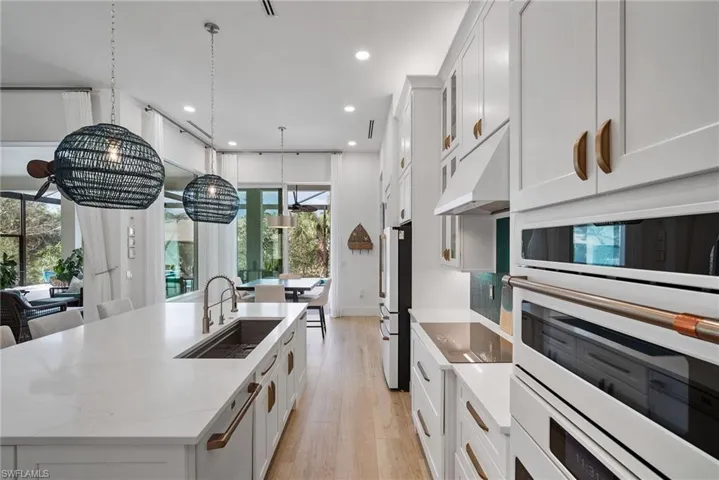 Kitchen featuring a center island with sink, white oven, white cabinets, and light hardwood / wood-style flooring