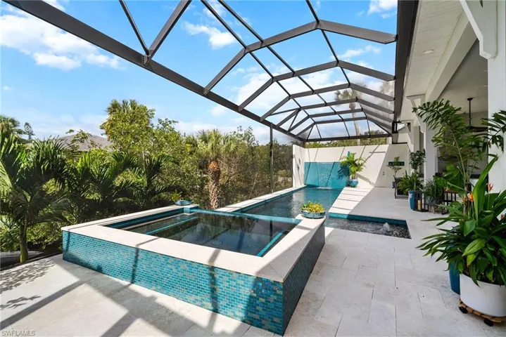 View of pool featuring a patio area, an in ground hot tub, and glass enclosure