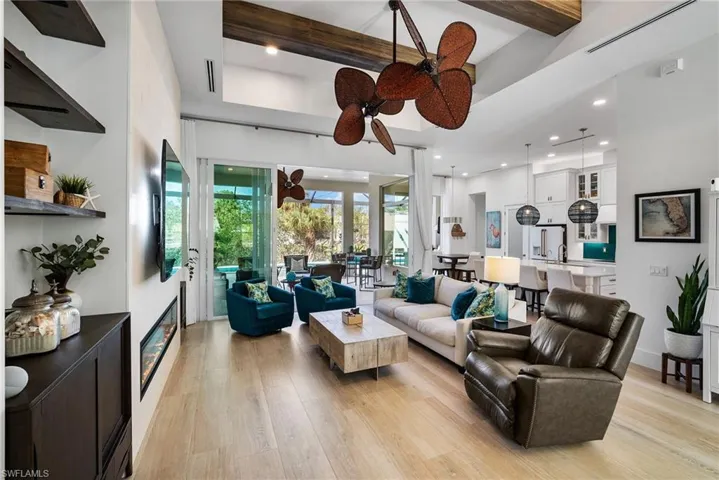 Living room featuring light hardwood / wood-style floors, a towering ceiling, beam ceiling, and ceiling fan