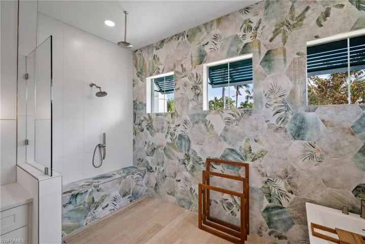Bathroom featuring a wealth of natural light, tile walls, a tile shower, and hardwood / wood-style flooring
