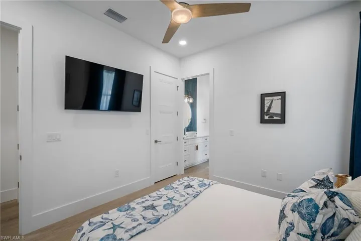 Bedroom featuring ceiling fan, ensuite bath, and light hardwood / wood-style floors