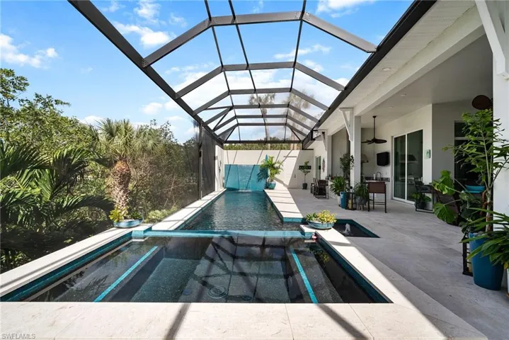 View of pool with a patio area, ceiling fan, an in ground hot tub, and glass enclosure