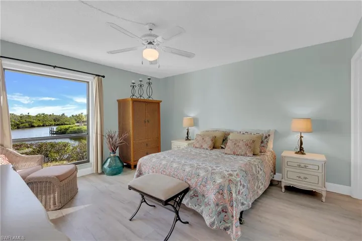 Bedroom featuring light wood-style floors, ceiling fan, a water view, and a textured ceiling