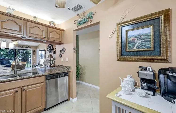 Kitchen with ceiling fan, dishwasher, light tile patterned floors, and dark stone counters