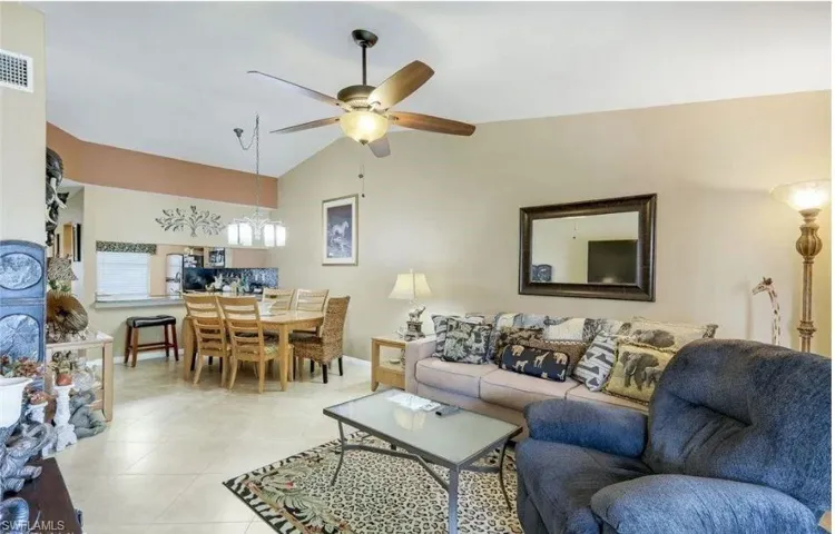 Living room featuring lofted ceiling, ceiling fan, light tile patterned floors, and hanging lights