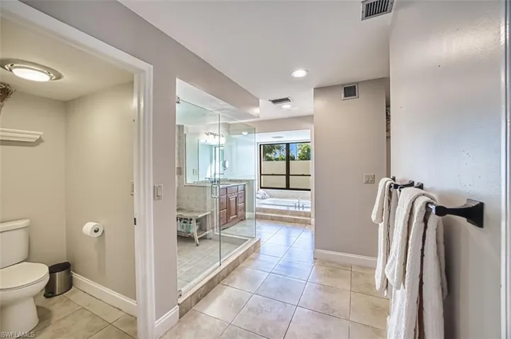 Full bathroom with light tile patterned floors, a garden tub, and a stall shower