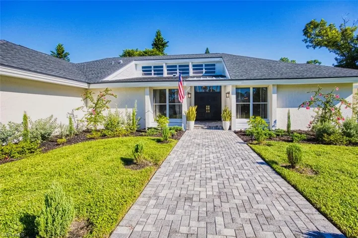 Mid-century home with stucco siding, a shingled roof, and a front yard
