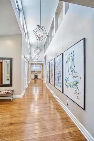 Hall with a chandelier, light wood-type flooring, and beverage cooler
