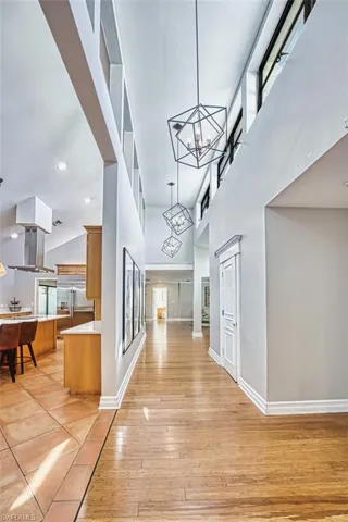 Corridor with a chandelier, a high ceiling, light wood-style floors, and recessed lighting
