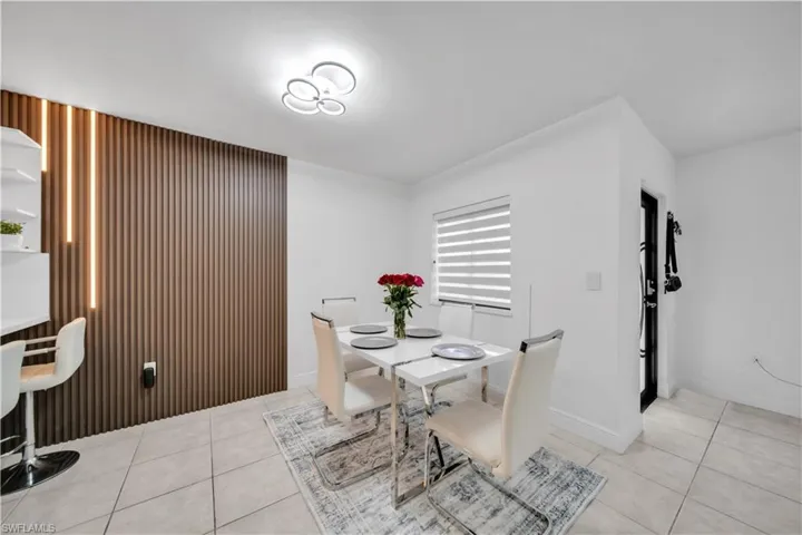 Dining area featuring a modern wood-slat accent wall with integrated vertical lighting, a contemporary ceiling fixture, and tile flooring