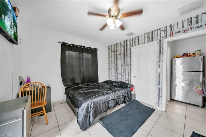 Room featuring tiled flooring, a ceiling fan with integrated lighting, and a window with dark privacy drapes