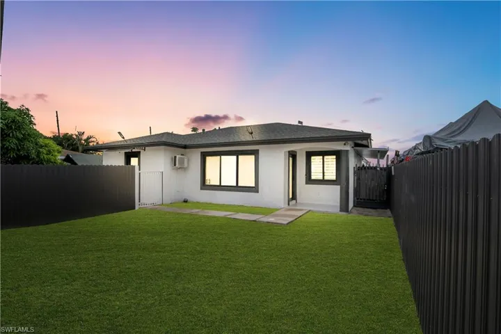 White stucco exterior with dark trim windows and a gray shingle roof