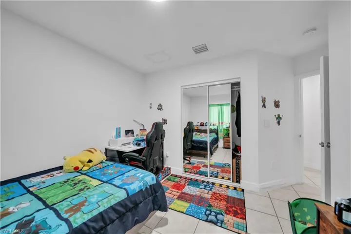 White walls, tile flooring, and mirrored closet doors