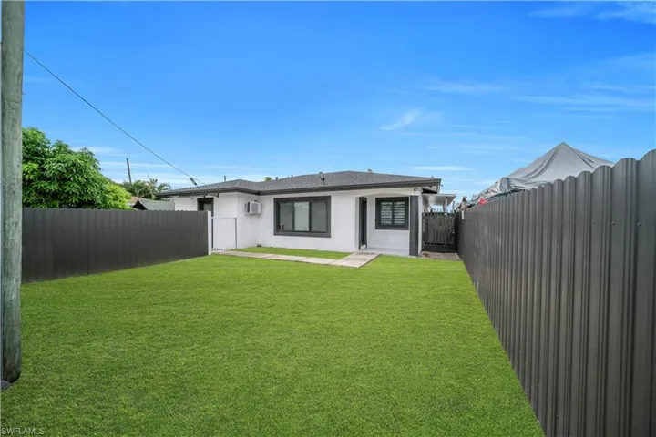 Expansive grass yard with dark corrugated panel fencing