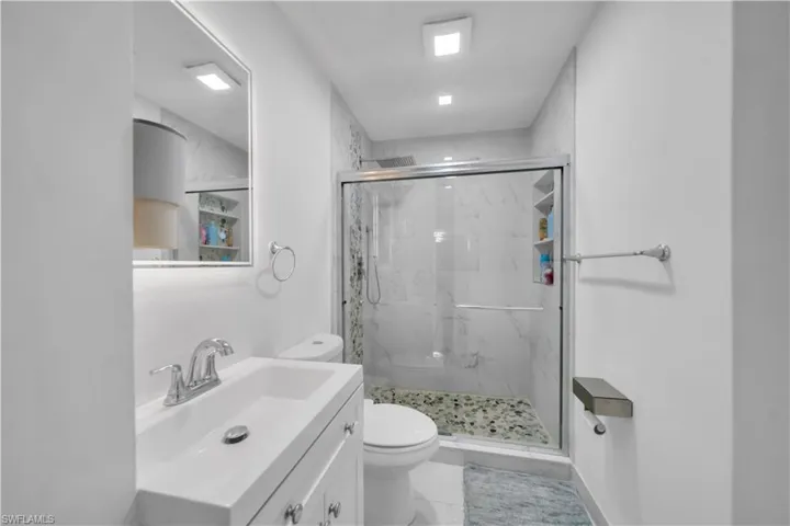 Contemporary bathroom featuring a white vanity with integrated sink, chrome fixtures, and a frameless glass shower enclosure