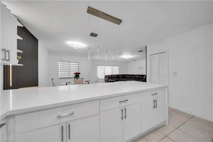 Contemporary kitchen island with white cabinetry and a light-toned countertop
