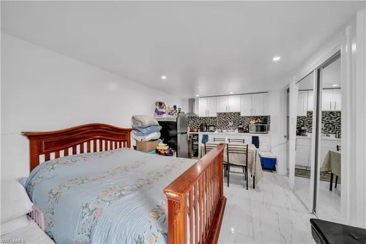 Open-concept living space featuring a wood-finish bed frame, recessed lighting, and large mirrored closet doors