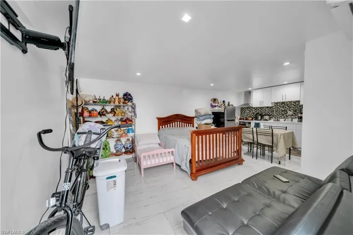 Open-concept living area featuring light-toned flooring, recessed lighting, and a kitchen zone