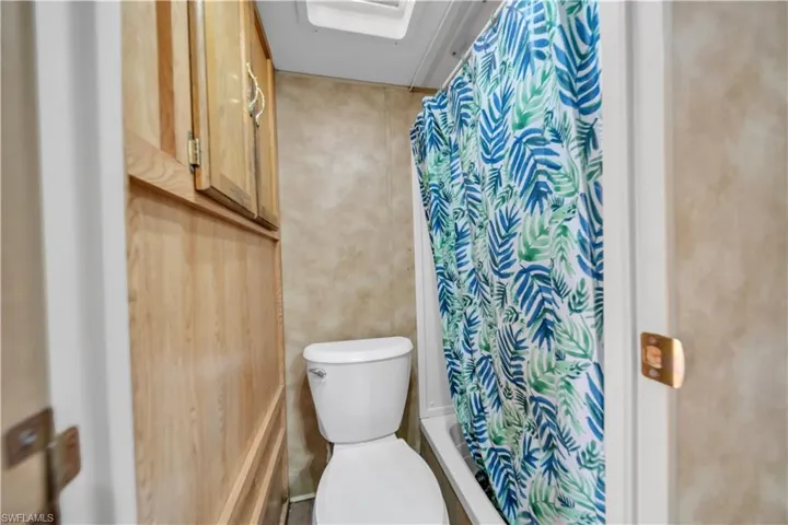 Compact bathroom featuring a white toilet and a built-in shower/tub combination