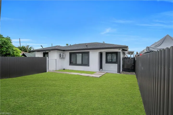 Modern stucco exterior with dark trim windows, a gray shingle roof, and a vibrant green lawn