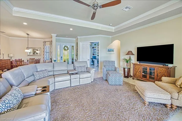 Tiled living area with recessed lighting, visible vents, ceiling fan, and ornamental molding