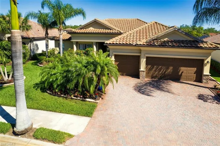 Mediterranean / spanish home featuring an attached garage, stucco siding, stone siding, a tile roof, and decorative driveway