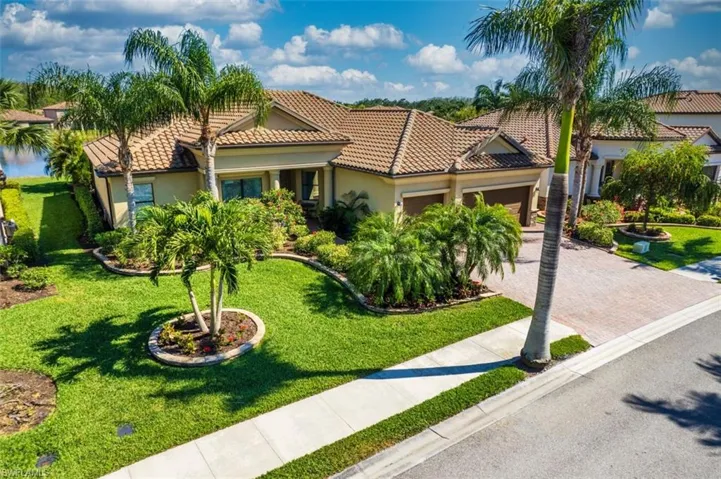 Mediterranean / spanish house featuring a front yard, a tiled roof, an attached garage, and stucco siding