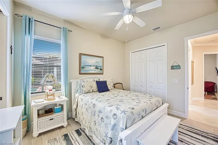 Bedroom with light wood-style tile flooring, ceiling fan, and a closet