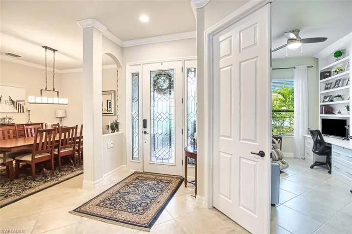 Entrance foyer with light tile patterned flooring and ornamental molding