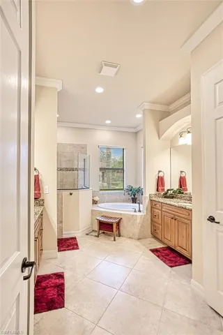 Full bath featuring vanity, a bath, tile patterned flooring, and ornamental molding