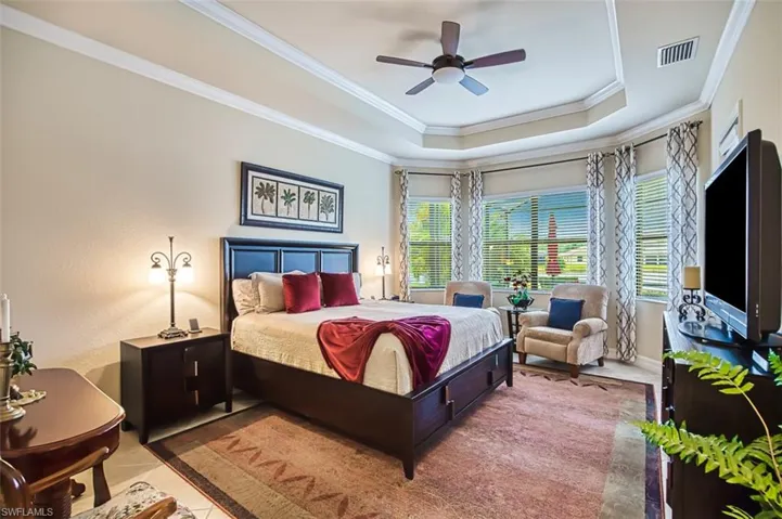 Bedroom featuring a tray ceiling, ceiling fan, ornamental molding, and tile patterned floors